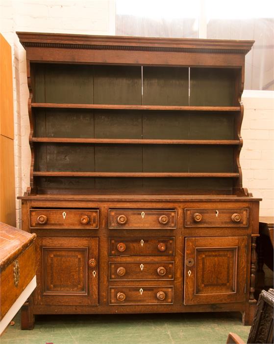 A Georgian oak dresser, the enclosed rack with three shelves above drawers inlaid with decoration.