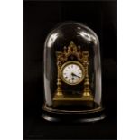 A miniature clock with glass dome and ebonised base, 20cm high.