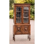 An oak bookcase, the upper section with two glazed doors, the lower section with carved panel doors.