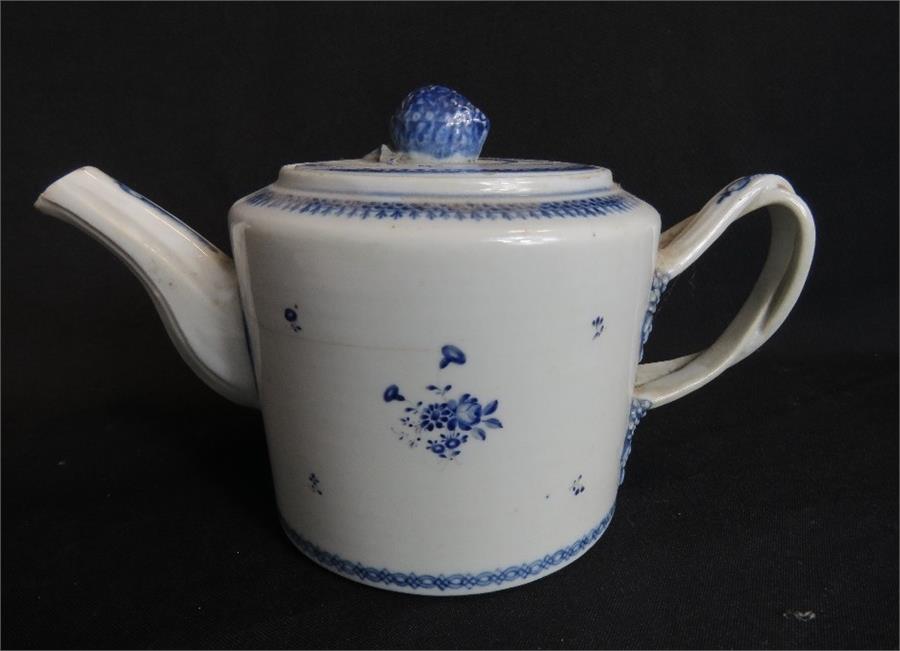 A blue and white porcelain tea pot with cross over handle.