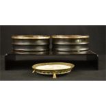 Two papier mache black lacquered wine coasters, and a porcelain coaster with brass border and