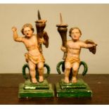 A pair of late 17th century carved polychrome cherub pricket stands, both winged cherubs holding a