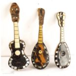 Three tortoiseshell musical instruments; two mandolins and one guitar.