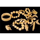 A group of bone carvings including a monkey brooch and beaded necklace.