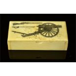 A bone carved pill box etched with a cannon, sword and gun.