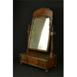 A Queen Anne period walnut toilet mirror, with three drawers, raised on bun feet.