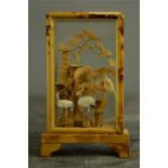 A small Chinese glass case containing cork carved display of two cranes amidst trees.