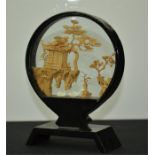 A small Chinese circular glass case with interior cork carved landscape of houses and trees.