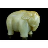 A jade carved Asian elephant with trunk turned upwards, rust inclusions.