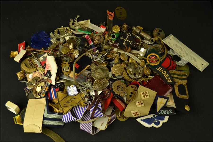 A large group of military cap badges, buttons, cloth badges, buttons etc.