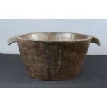 A treen deeply recessed bowl carved from the solid with integral handles.