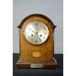 An Edwardian mahogany mantle clock, with silvered dial, inlaid oval and presentation plaque.