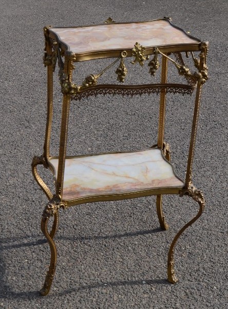 A French ormolu and marble two tier table, adorned with gilt metal swags and face masks, 83 by 52 by