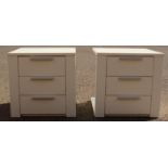A pair of white bedside tables with three drawers.