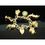 A 9ct gold charm bracelet, with seven charms and a heart form clasp and safety chain, 52.70g.