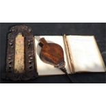 A pair of bellows, a carved walnut panel, and a leather bound ledger book.