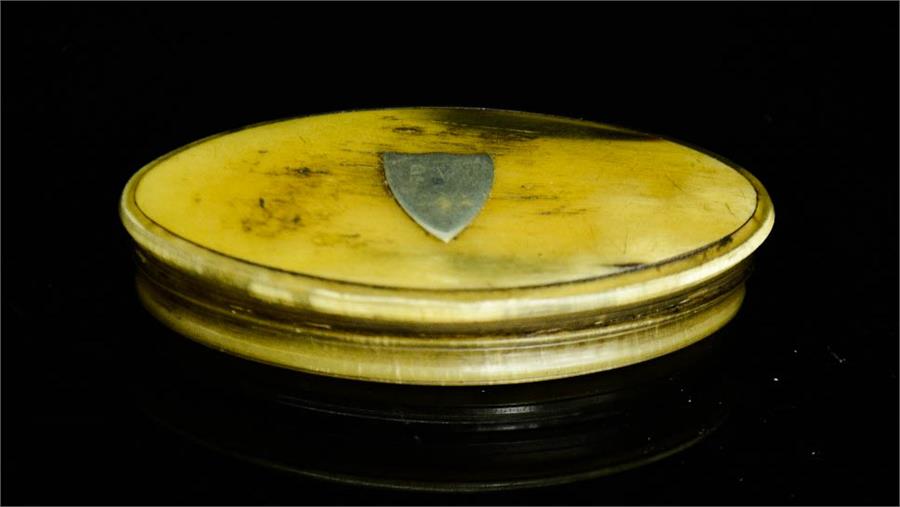 A 19th century horn snuff box, oval form, inset with a shield to the lid, 85 by 45cm.