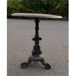 A cast iron table with circular top and the base composed of cast dolphins.