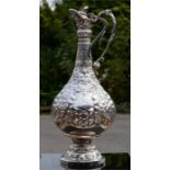 A silver claret jug, embossed with floral decoration, with presentation inscription to the front,