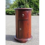 A bedside cabinet, drum form with single drawer and cupboard door.
