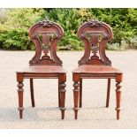 A pair of Victorian mahogany hall chairs, with carved backs.