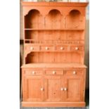 A pine dresser and rack, the enclosed back with triple arch front above four drawers, the base