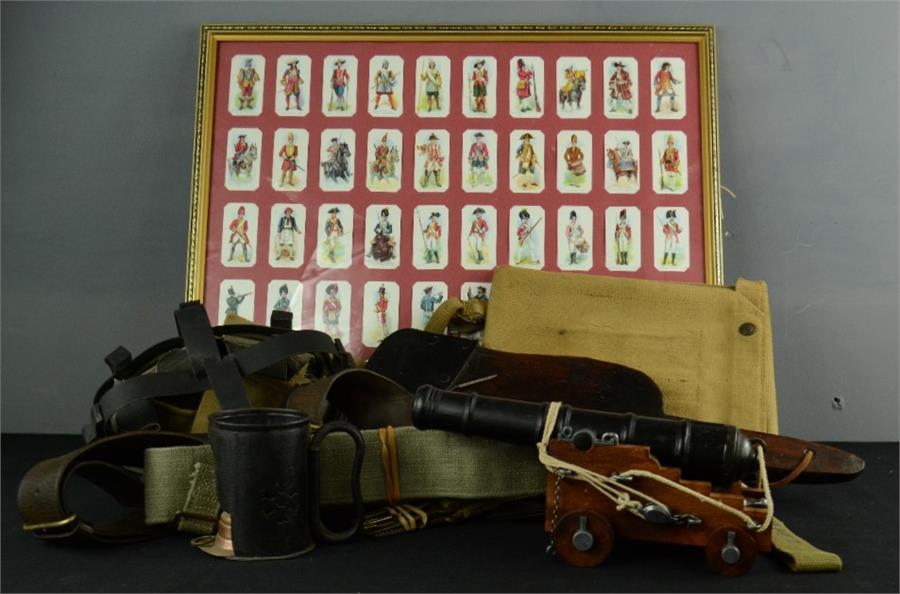 A miscellaneous group of items to include cigarette cards, framed, a treen shovel, a model cannon,