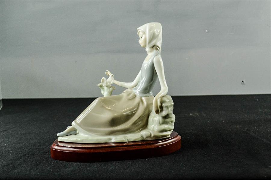 A Lladro figurine, girl seated beside a white bird, 17cm high.