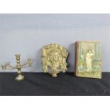 A miniature brass candleabra, a French gilt metal cherub head, and a book.