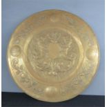 A brass charger, embossed with a crest to the centre, 58cm diameter.