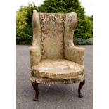 A Victorian mahogany framed wingback armchair, with original silk print upholstery.