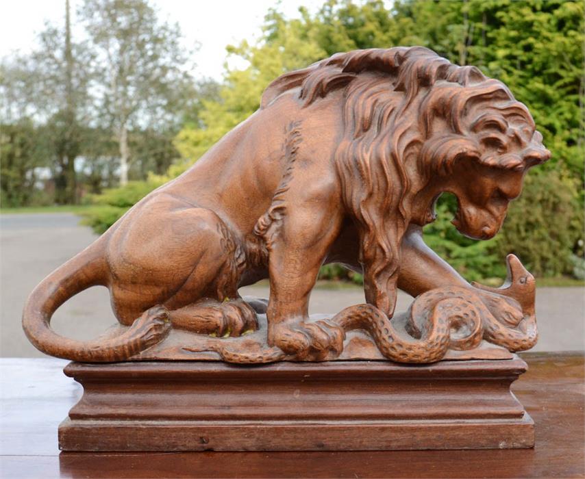 A carved treen lion & serpent, raised on a platform, 23 by 31 by 10½cm.