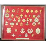 A group of military badges in a box frame, including cap badges.