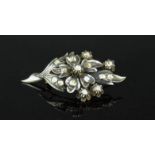 A white metal and diamond brooch, in the form of a floral spray, 0.74toz.