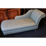 Reproduction chaise longue upholstered in a seagreen floral pattern fabric raised on turned