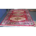 Indian carpet with three cream lozenges on a red ground, 354cm x 274cm.