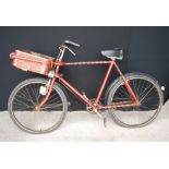 Vintage red and black painted gents bicycle with a frame mounted front delivery tray.