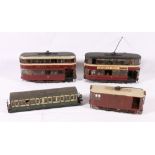 Three unattributed O gauge electric operated tram cars and a passenger coach.