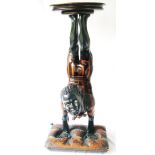 Blackamoor figure of a boy doing a handstand with cushion form base and circular top.