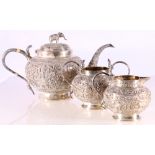 Indian white metal three piece teaset, chased and engraved with natives on foliate landscapes,