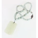 Carved jade pendant of rectangular shape on green hardstone necklace with sterling silver clasp.