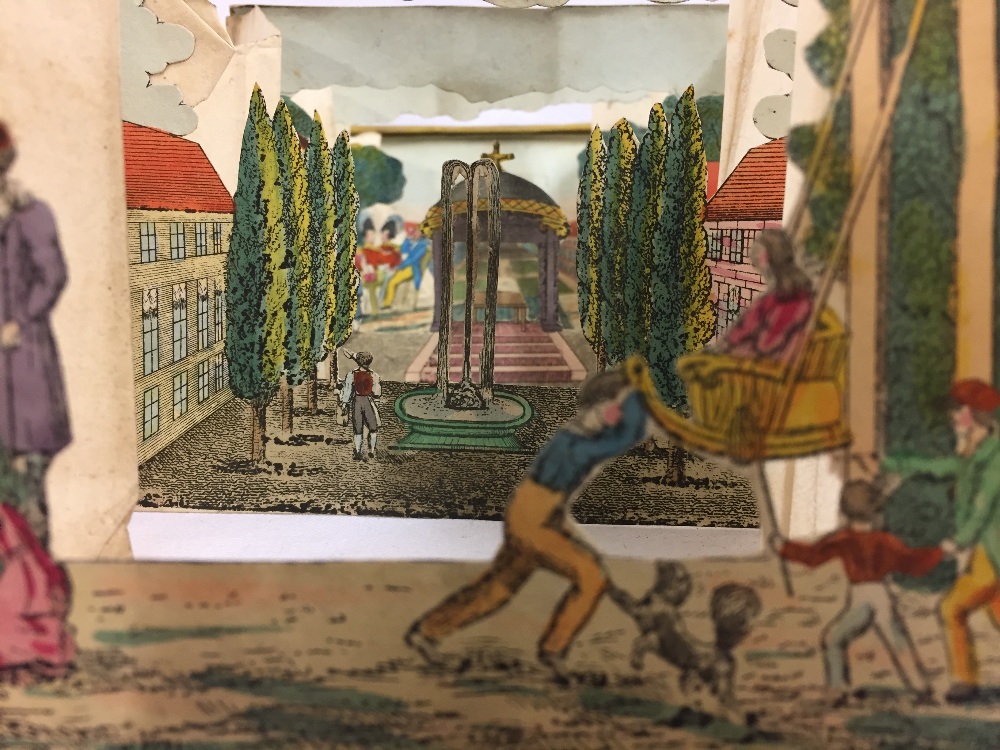 19th century peepshow with five accordion sections depicting figures in a garden landscape,