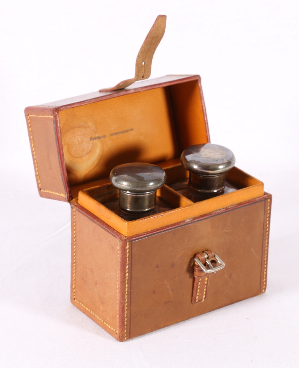 Pair of silver topped toilet bottles, in leather case initialled EC, London 1919, case 11.5cm tall.