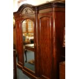 Victorian mahogany triple door wardrobe with central mirrored door raised on plinth base,
