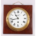 Brass bulkhead clock on a mahogany plaque,