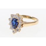 Sapphire and diamond ring with central teardrop sapphire encircled by ten round cut diamonds.