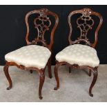 Pair of Victorian carved rosewood side chairs with pierced splats and cabriole legs.