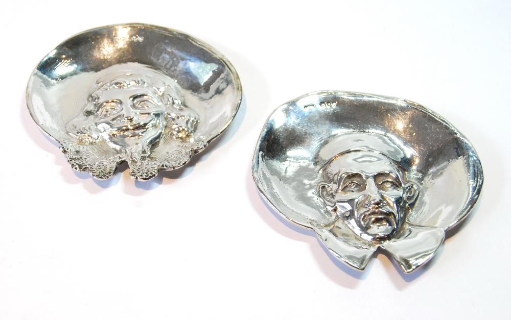 Pair of silver ashtrays, one embossed with the head of a Cleric with bonnet and wide lapels,