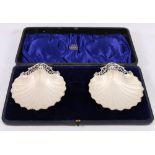 Cased pair of silver shell butter dishes, with pierced handles and glass liners, Chester 1904,