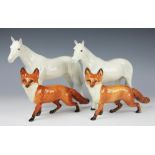 Two Royal Doulton dappled grey horses, 20.5cm high and two Beswick foxes 13.